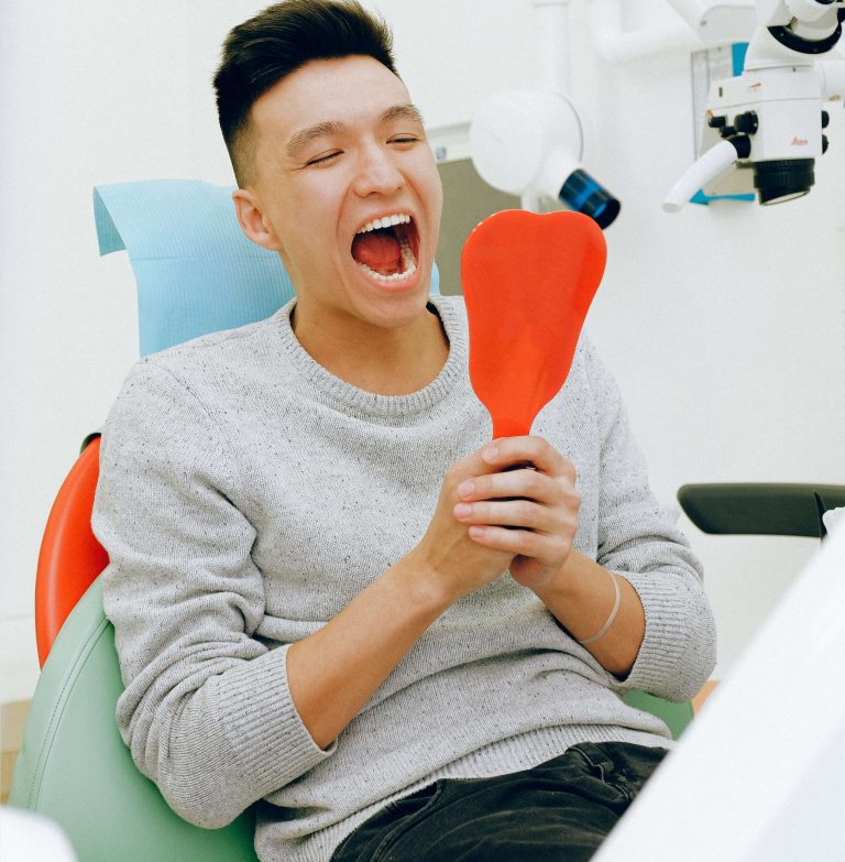 Man Looking Into Mirror After Cleaning Between Teeth